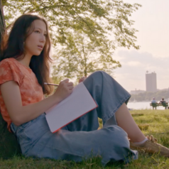 girl writing in a notebook outside