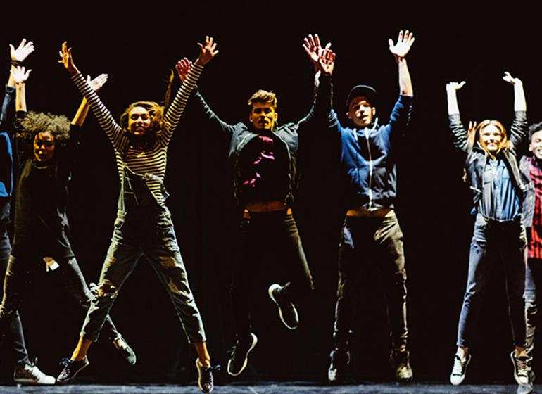 a group of performers leaps into the air on stage