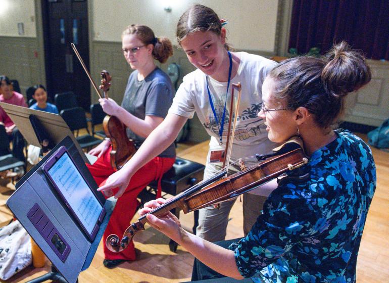 Students practice the violin in a classroom
