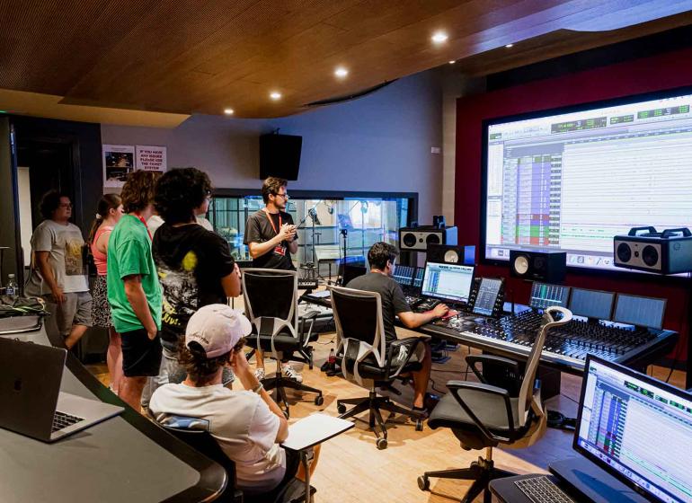Students in a music production studio on the Berklee Valencia, Spain campus listen intently as a Berklee instructor teaches music production.