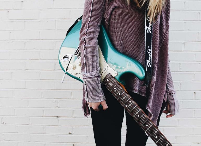 Woman  holding a guitar, ready to play.