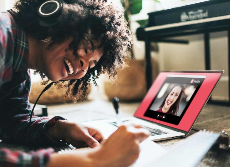 Woman writing songs, with notes, and laptop open.