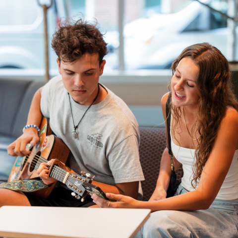 Man playing guitar sitting next to a girl singing