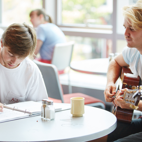 Two students working on a song together sitting at a table