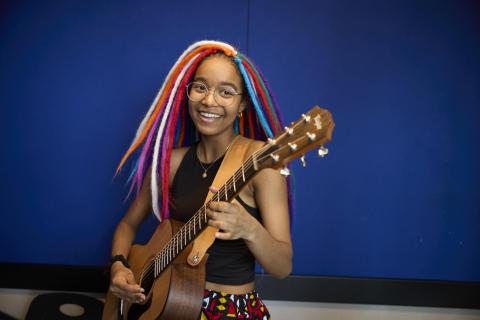 a young woman smiling and holding an acoustic guitar