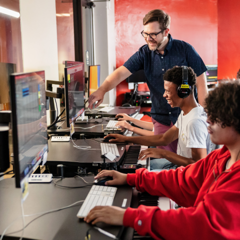 Teacher helping student who is sitting at the computer